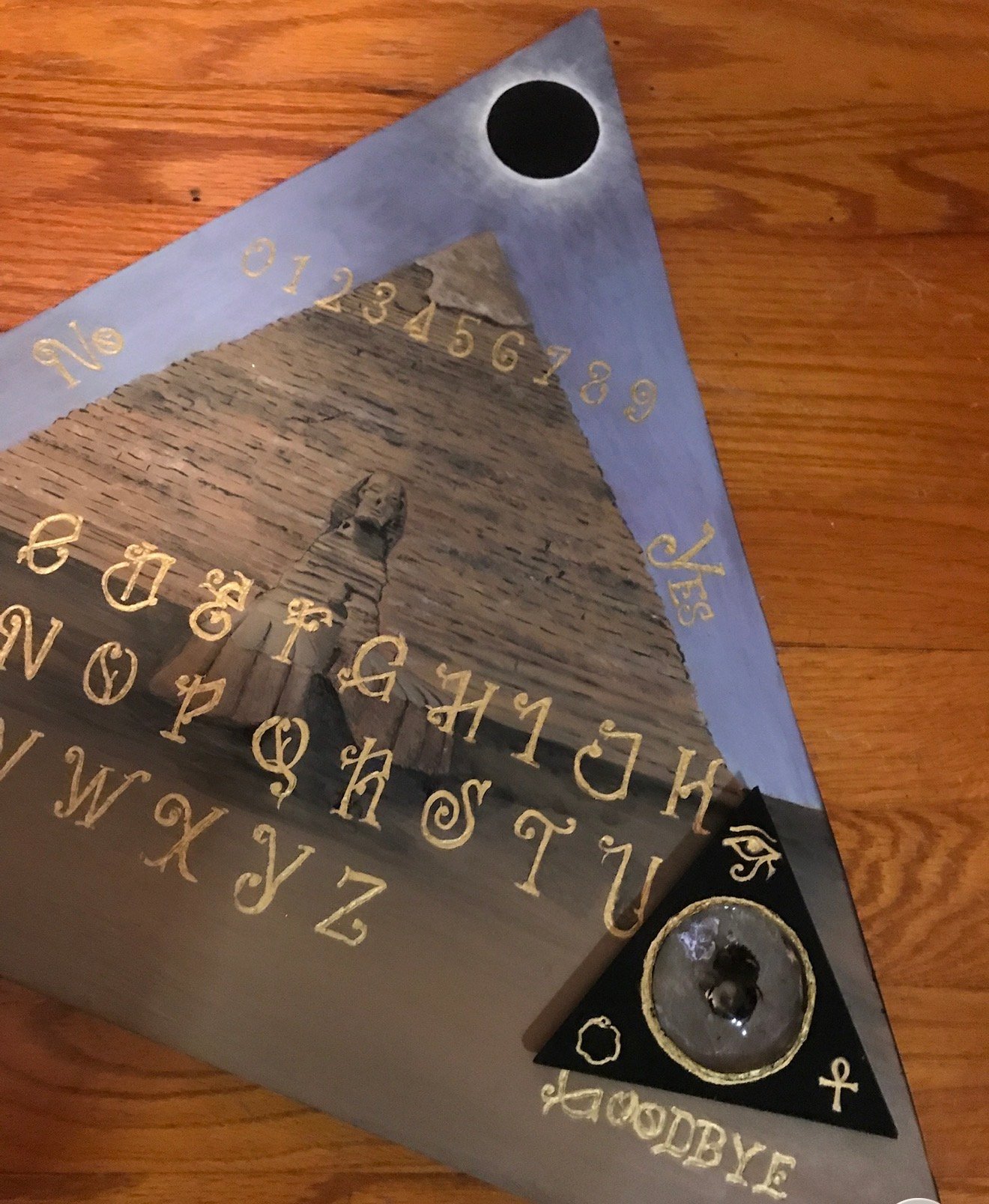 Triangular Egyptian-themed spirit board with pyramid and Eye of Horus by Loren Morris